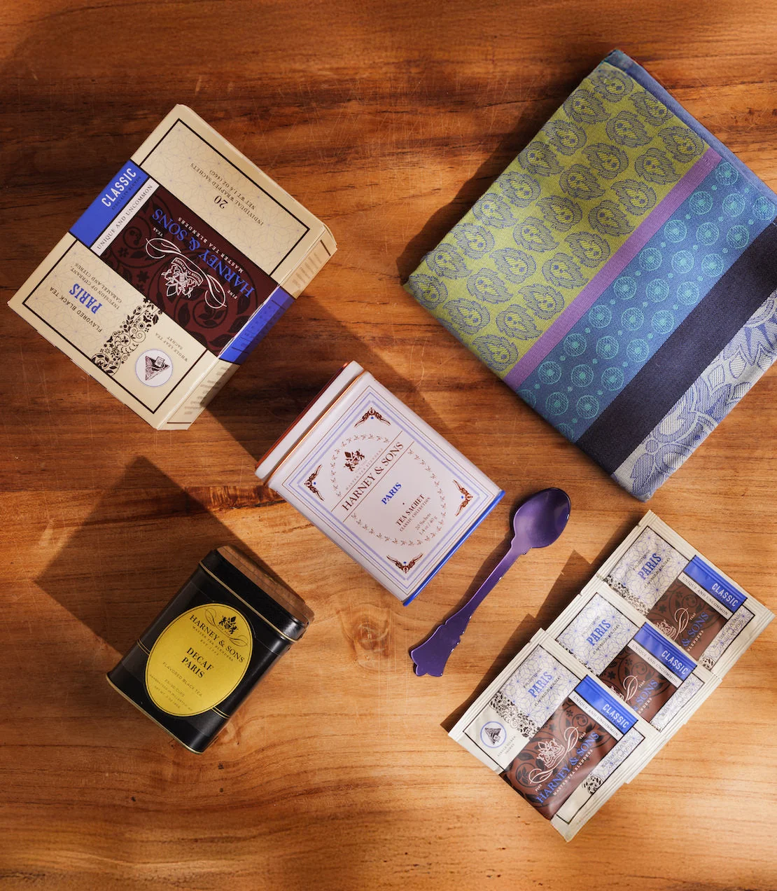 Harney & Sons Paris gift contents arranged on a wooden table with tea packets and a folded towel