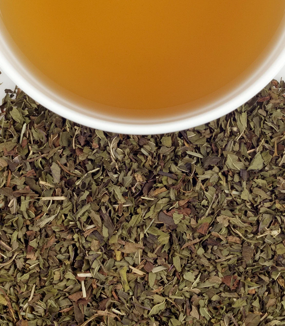 A cup of Harney & Sons Peppermint Herbal beside dried peppermint leaves