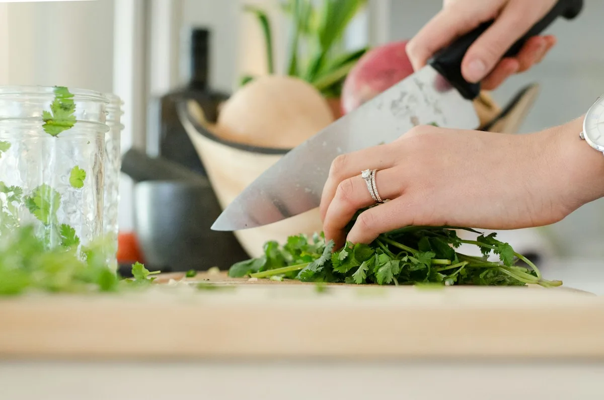 Hands chopping fresh green herbs on a kitchen board