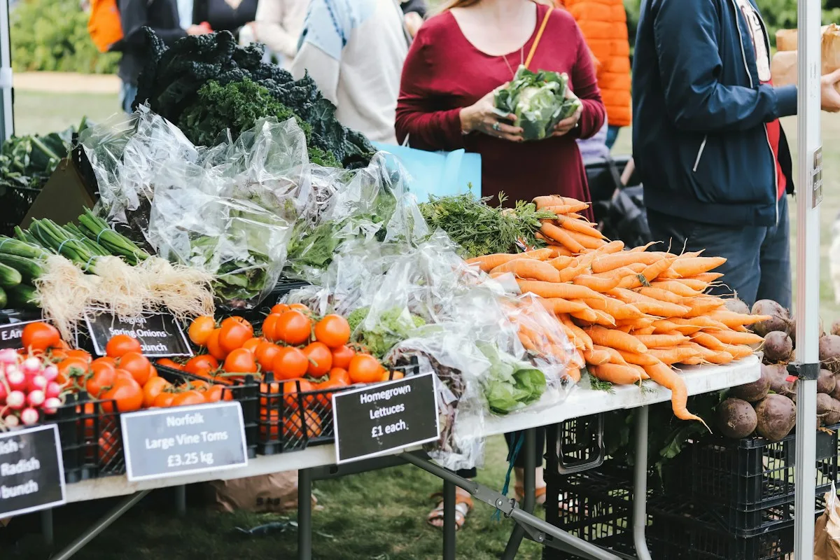 Shoppers beside fresh vegetables at an outdoor produce market
