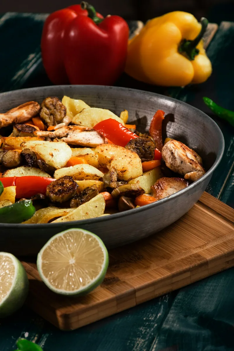 A skillet filled with cooked vegetables and a lime wedge nearby