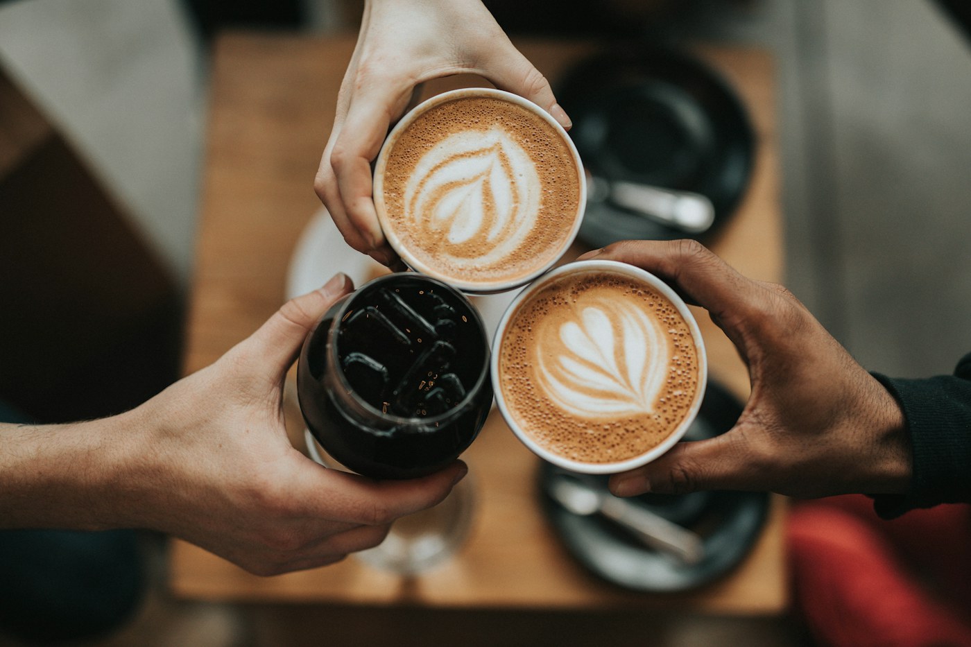 Hands holding cups of coffee with latte art