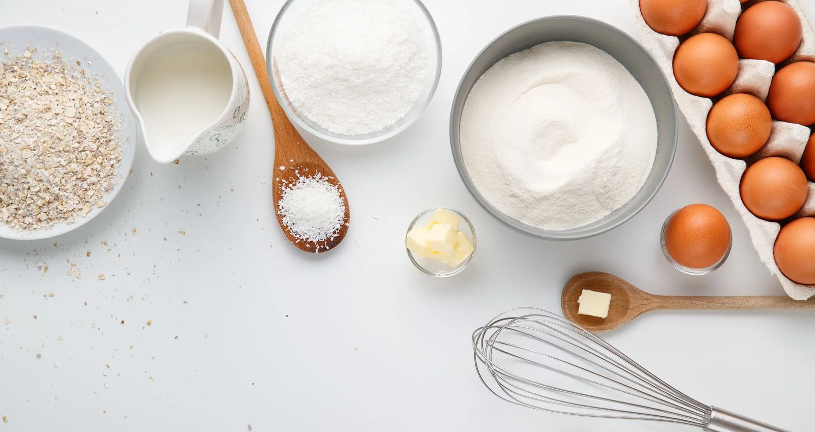 Bowls of baking ingredients, eggs and utensils on a work surface