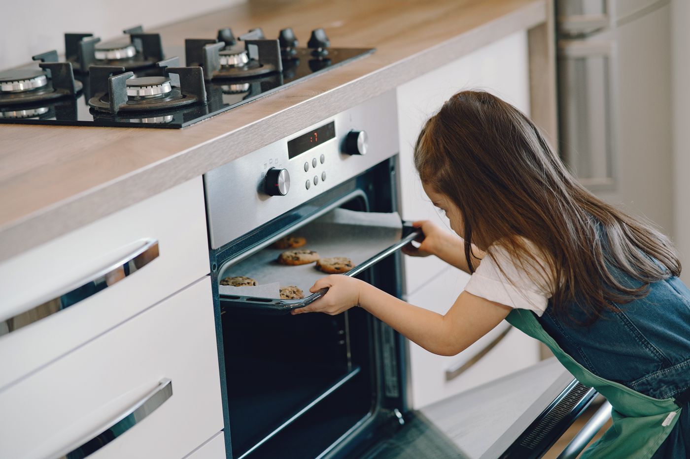 A woman placing a tray into an open oven