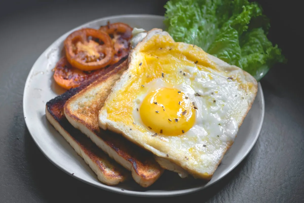 Fried egg and toast with tomatoes and greens on a plate.
