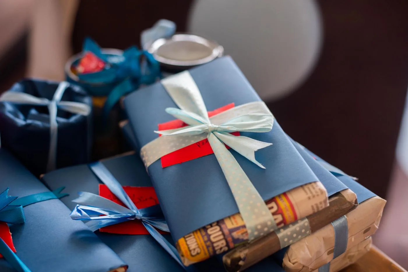 Wrapped gifts with blue ribbons beside other presents.