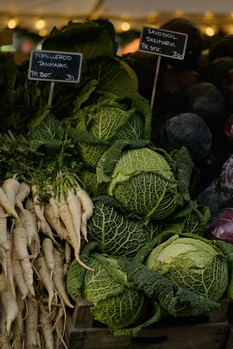 Cabbages and pale root vegetables displayed at a market.