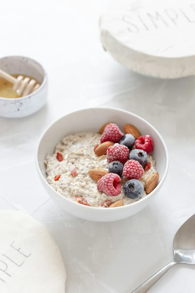 An oat bowl topped with berries beside breakfast dishes.