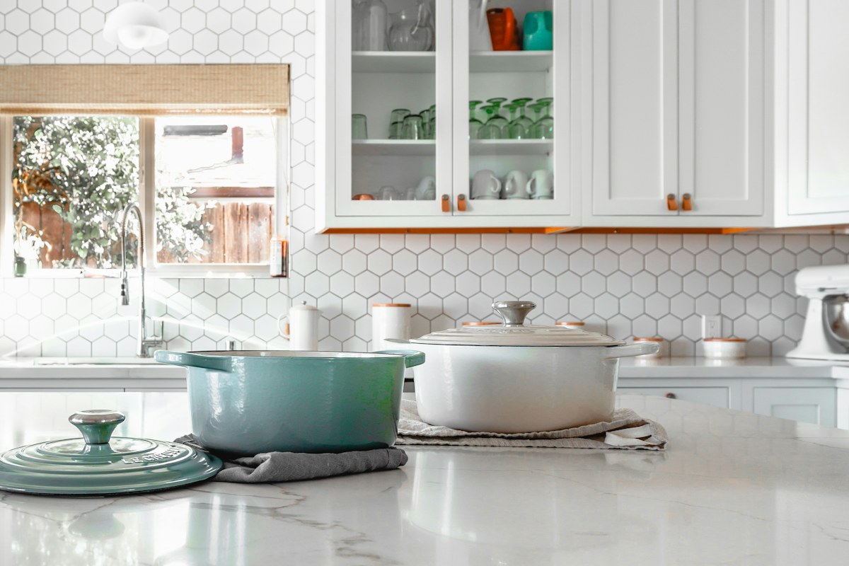 Cooking pots and matching lids on a bright kitchen counter.