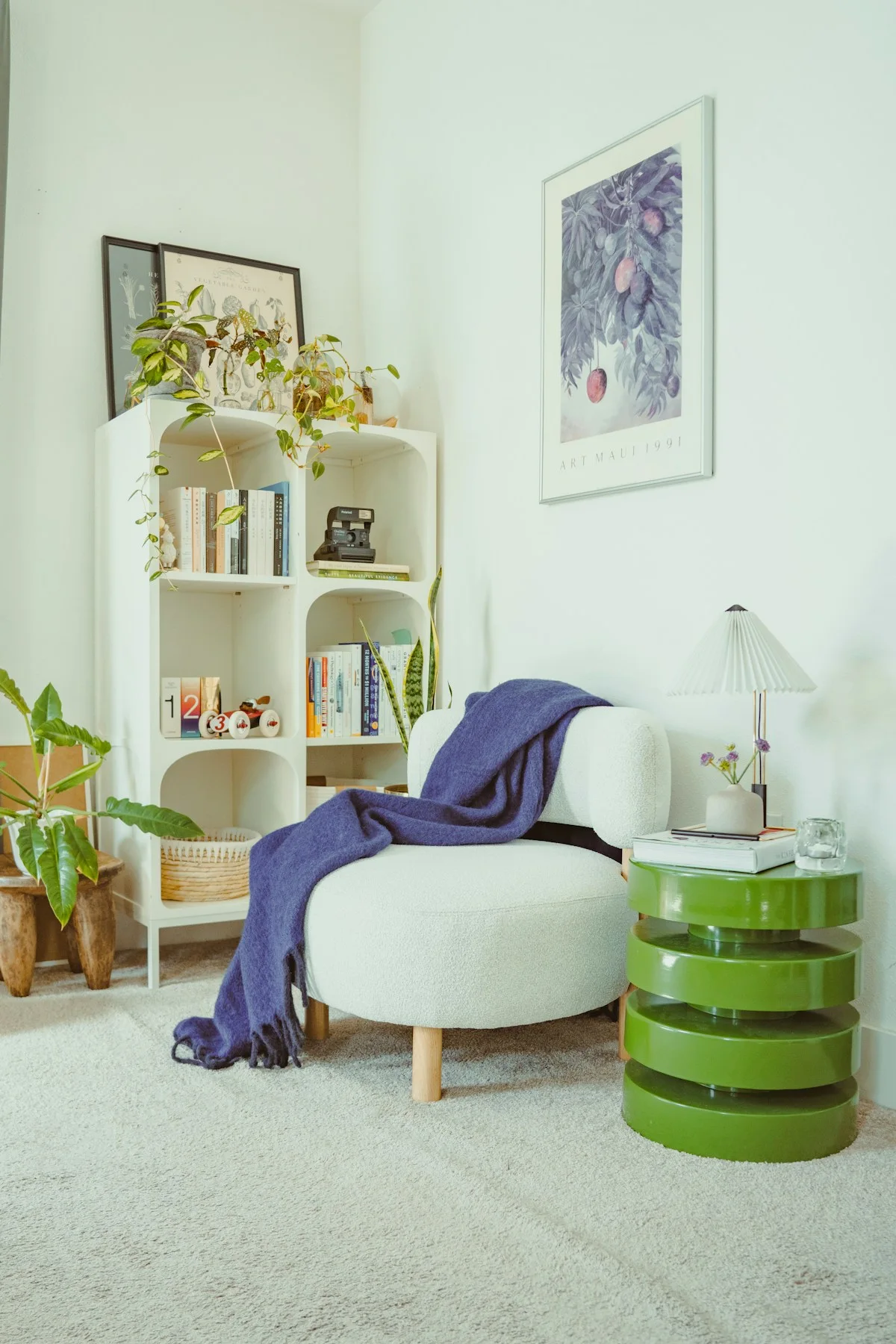 A light armchair with a throw beside a green side table.