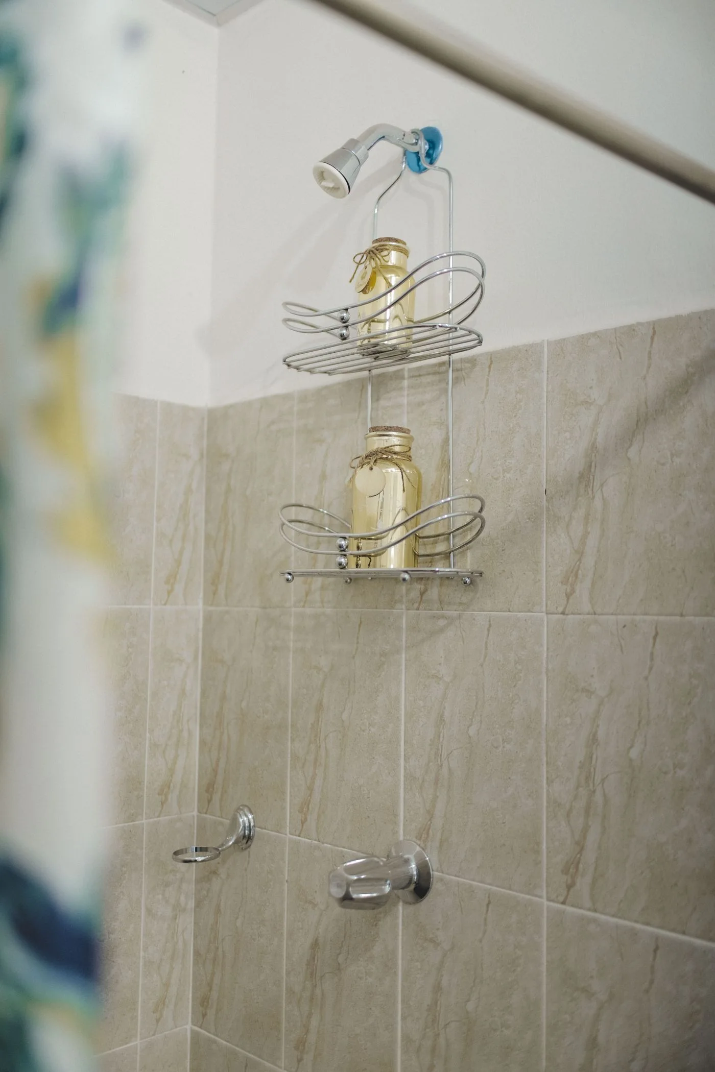 Wire shower shelves holding bottles against tiled walls.