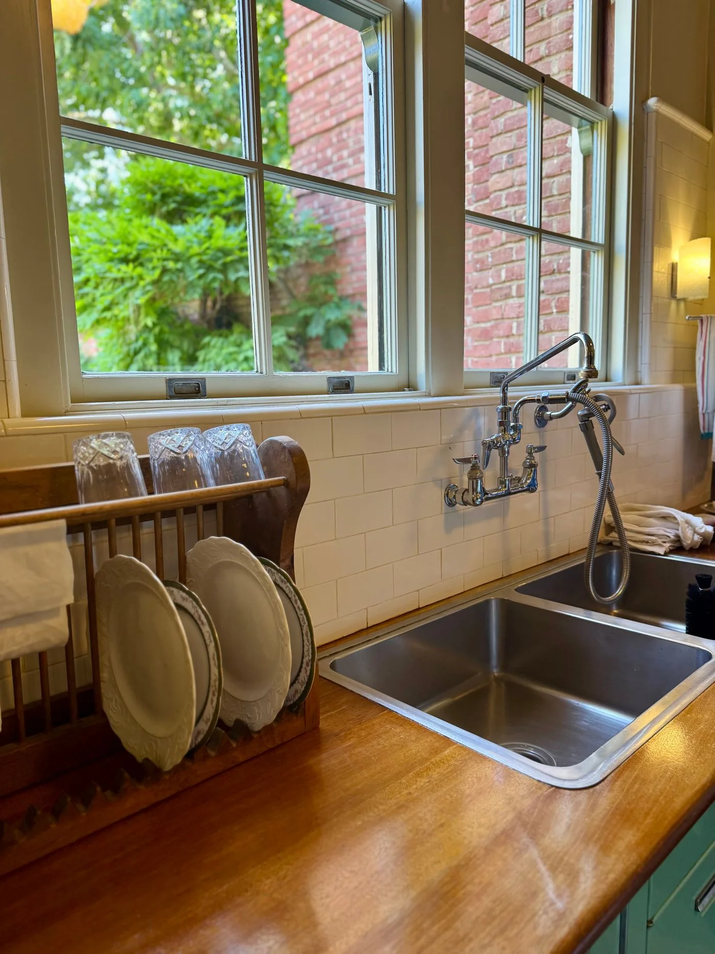 A kitchen sink with plates stored beside a window.